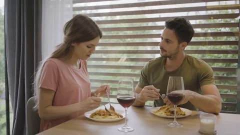 Cute young couple eating dinner together and making toast with wine while cha Stock Footage 79798952
