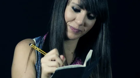 Cute young girl taking notes on a notepad with a pencil; writing, 4k, uhd Stock Footage 42419752