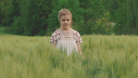 Cute young girl walks in the field of the green wheatfield. Slowly Stock Footage