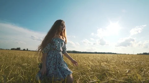 A cute young girl walks by herself in a golden field of wheat Stock Footage