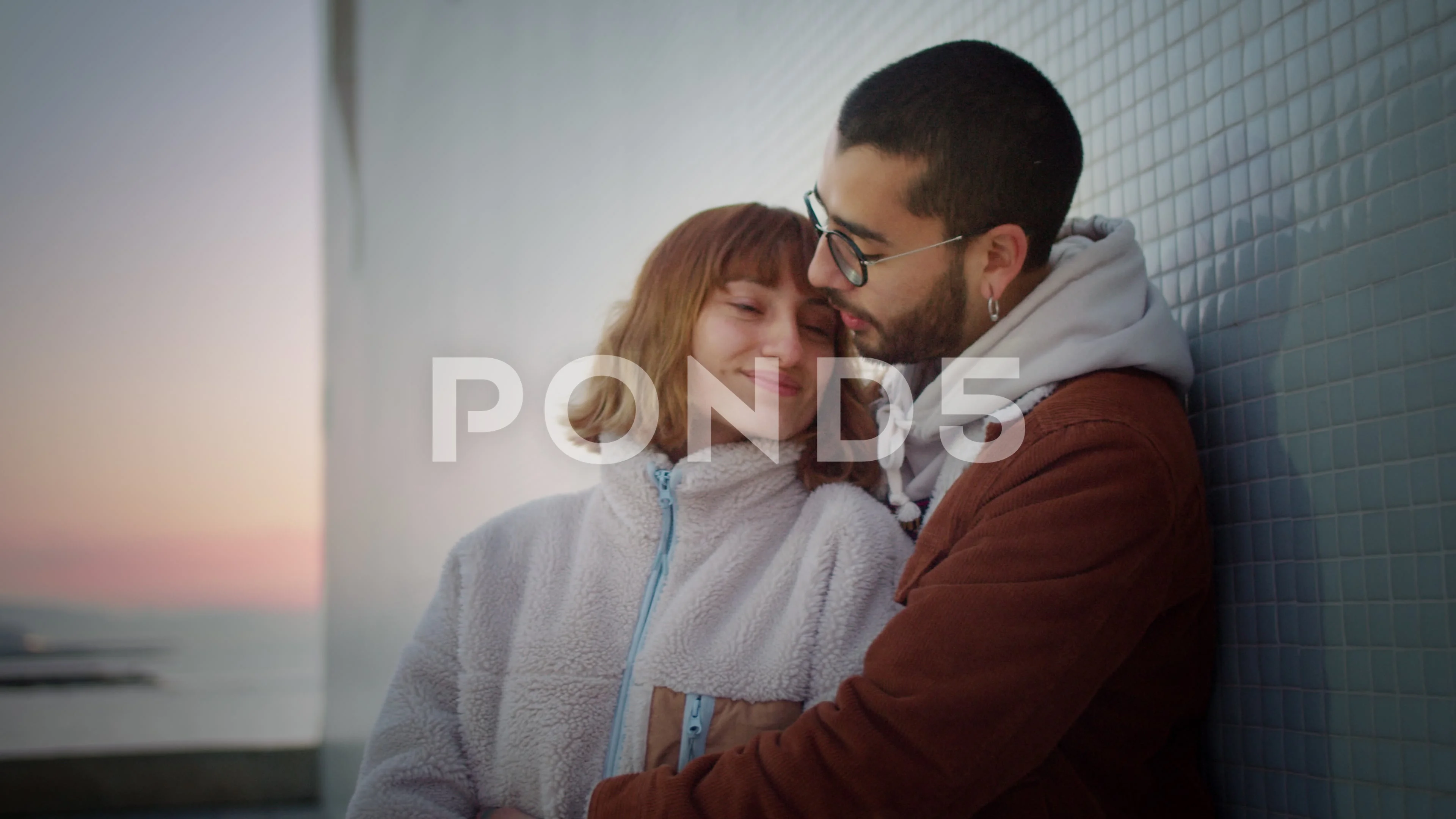 Cute young Hispanic couple in love cuddling tender sunrise leaning on white  wall