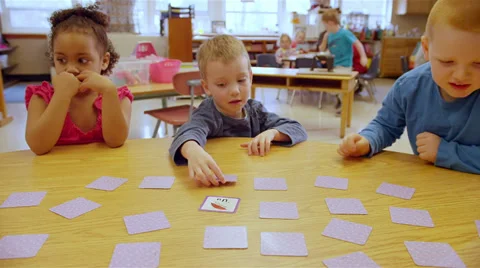 Cute young kids sit around a table at school and play a learning game Stock Footage 34004632