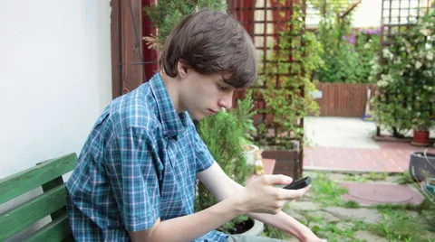 Cute young man surfing on internet, smartphone, cell, home garden Stock Footage 51678038