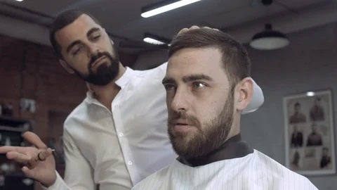 Cute young mixed race barber with beard shows his client how to adjust the beard Stock Footage 112347650