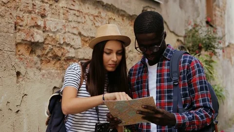 Cute young multi-ethnic couple of tourists searching the road on the paper map Stock Footage 81774041