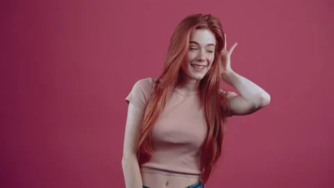 Cute young redhead of 20 years, in a pink casual T-shirt, isolated on a pink Stock Footage 150409462