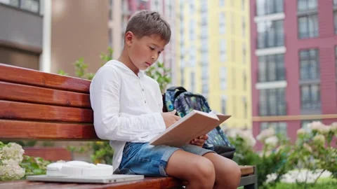 Cute Young School Guy is Reading Book Outside while Sitting on Bench. Stock Footage 249211497