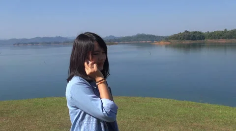 Cute young woman in the mountains in front of lake talking on the phone smile. Stock Footage 59081944