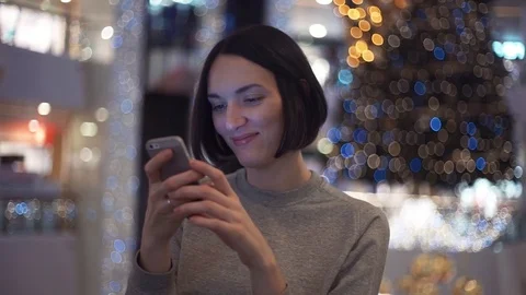 Cute young woman smiling using smartphone in shopping mall. Slow motion Stock Footage 83364329