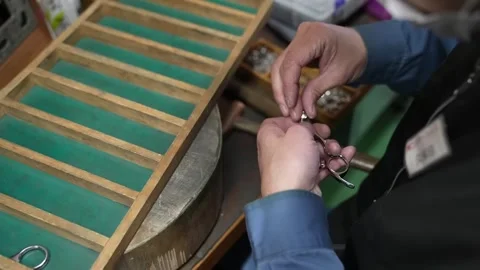 Cutler fits the pivot screw into a pair of handmade scissors at a traditional Vídeo Stock 346737694