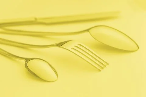Cutlery set on background, colored in yellow. Stock Photos