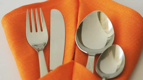 Cutlery set. Fork, knife, spoon and teaspoon in textile napkin on table Video stock 93877348