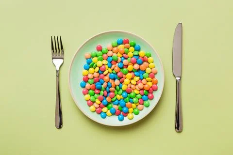 Cutlery on table and sweet plate of candy. Health and obesity concept, top vi Stock Photos