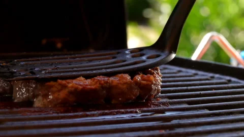 Cutlet for a burger is pressed with a spatula to the grill and burst into flames Stock Footage 127644469