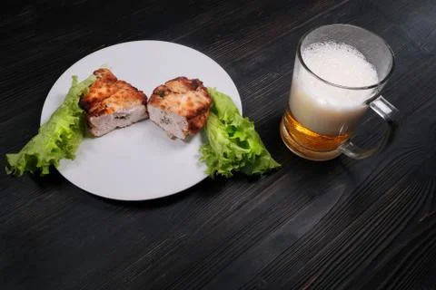 Cutlet with stuffing, breaded with lettuce. A large mug of beer next to a chi Stock Photos
