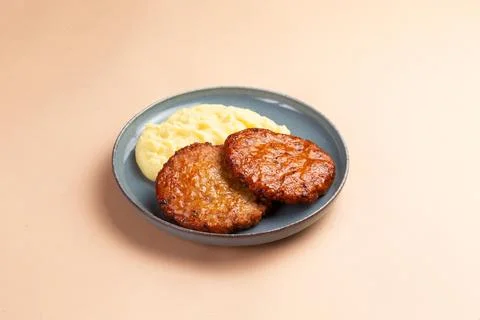Cutlets and mashed potatoes in a plate on a light background. Stock Photos