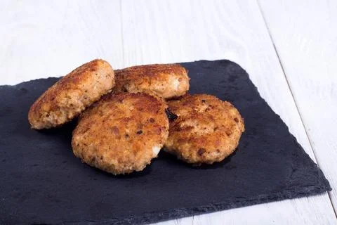 Cutlets on a black flat plate, on a white wooden background Stock Photos