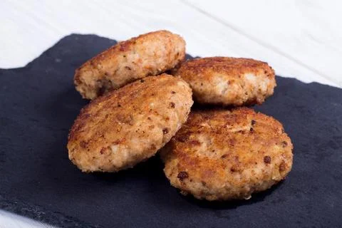 Cutlets on a black flat plate, on a white wooden background Stock Photos