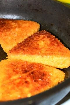 Cutlets of triangular shape are fried in a frying pan. 스톡 사진