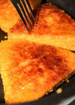 Cutlets of triangular shape are fried in a frying pan. Stock Photos