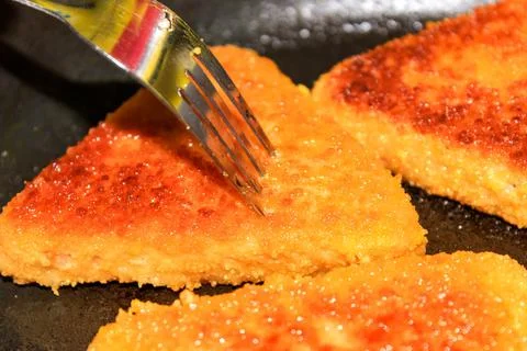 Cutlets of triangular shape are fried in a frying pan. 스톡 사진