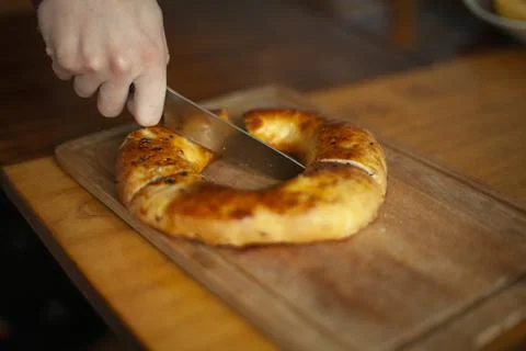 Cuts bread with a knife. Ruddy bread made of flour. Food for breakfast. Stock Photos