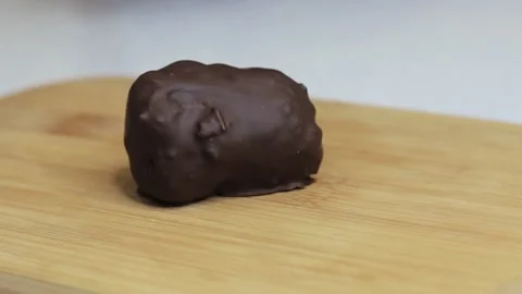 Cuts a coconut candy in half with a knife. Stock Footage 130231296