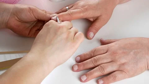 Cuts the cuticle with a manicure scissors.Hands close-up on a white table. Stock-Footage 140091067