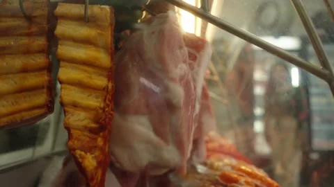 Cuts of Raw Meat Hanging in a Refrigerated Shop Display Stock Footage 340300194
