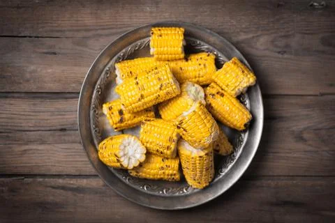 Cutted corn cobs on the brown rustic plate at the center of image Stock Photos