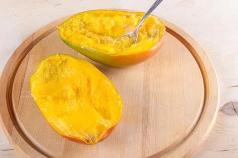 Cutted in halves mango on woden table Stock Photos