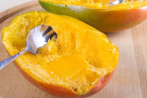 Cutted in halves mango on woden table Stock Photos