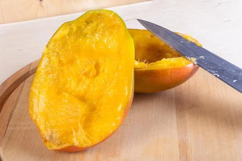 Cutted in halves mango on woden table Stock Photos