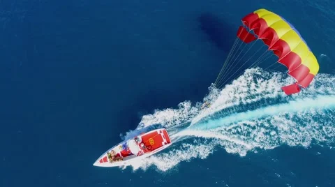 Cutter pulls parachute with people which fly above sea at summer Stockbeeldmateriaal 58503809