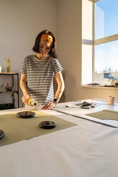 Cutting and sewing in tailor studio: sewer young woman work with fabric in Stock Photos