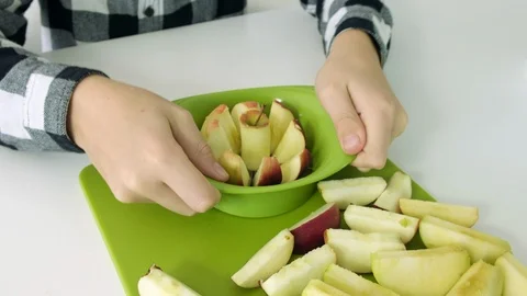Cutting apple with kitchen knife on green board, white background, close up foot Stock Footage 102787314