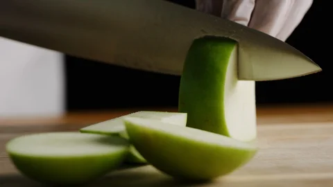 Cutting apples with chef knife macro shot Stock-Footage 128490346