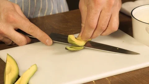 Cutting of an avocado by a chef in uniform, close up Stock Footage 121098173