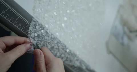 Cutting beads with scissors on white fabric in the manufacture of dresses Stock Footage 167694518