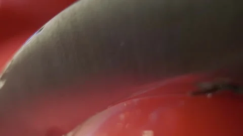 Cutting beautiful red tomato using kitchen knife, water drops macro video. Fresh 動画素材 147934214