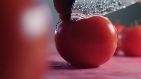 Cutting beautiful red tomato using kitchen knife, water drops macro video. Fresh Stock Footage 147934327