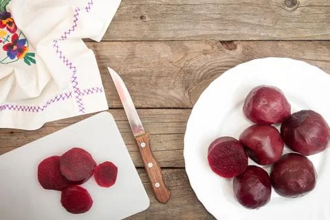 Cutting beetroot on white chopping board over on old wooden table. Stock Photos