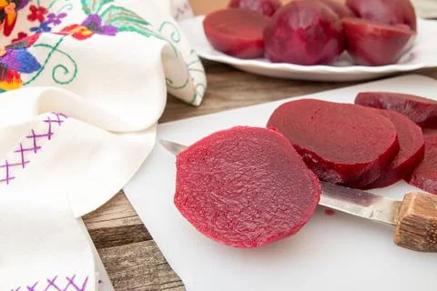 Cutting beetroot on white chopping board over on old wooden table. Stock Photos