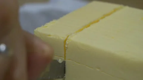 Cutting a big chunk of butter slice with a knife, extreme close-up view Vidéo 262752839