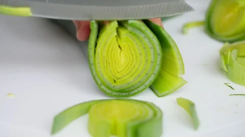 Cutting a big leek on white surface shallow depth of field focused further Vidéo 107012242