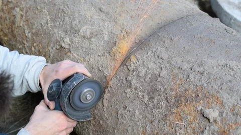 Cutting big rusted iron pipe with an angle grinder outdoors Stock Footage 73828233