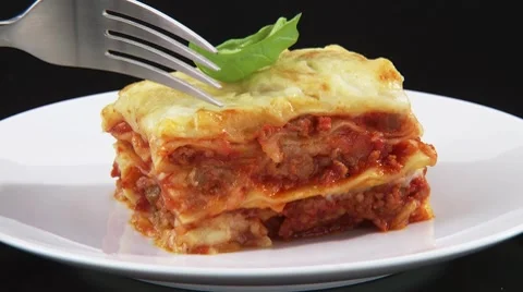 Cutting a bite-sized piece of lasagne with a fork Stock Footage 8571519