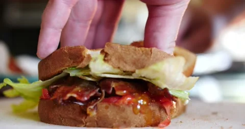 Cutting a BLT sandwich in half ready to be eaten side view Stock Footage 206575466