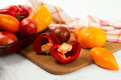 Cutting board with assort of different tomatoes and bell pepper on white wo.. Stock Photos
