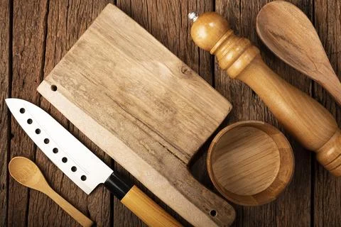 Cutting board with kitchen utensils on rustic background. Stock Photos